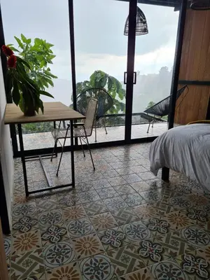 a room with a bed and a table and a window at Lodge Paraíso Verde in Manizales