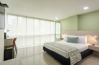 a bedroom with a large bed and a mirror at Hotel Suite Comfort in Medellín