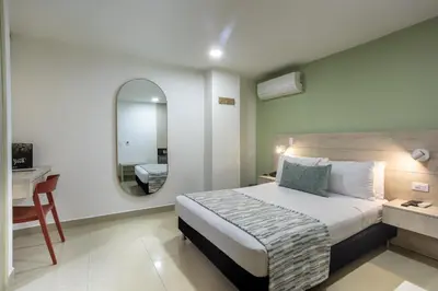 a bedroom with a bed and a desk and a mirror at Hotel Suite Comfort in Medellín