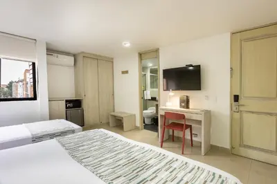 a hotel room with two beds and a desk and a television at Hotel Suite Comfort in Medellín