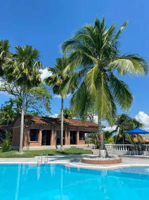 a pool in front of a house with palm trees at La Manola Finca Hotel in Doradal