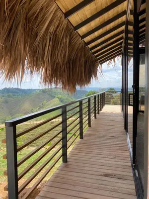 a wooden boardwalk with a thatched roof on a building at La Manola Finca Hotel in Doradal