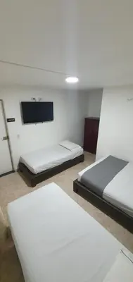 a room with two beds and a flat screen tv at Hotel Gran Imperio in Medellín