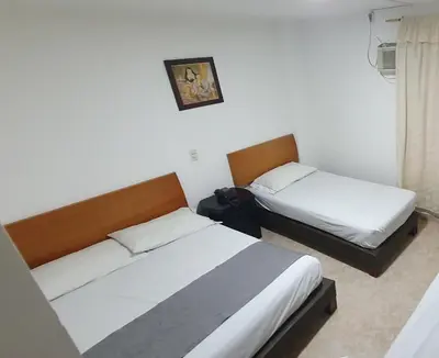 a bedroom with two beds and a picture on the wall at Hotel Gran Imperio in Medellín