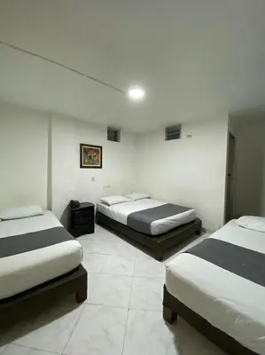 three beds in a room with white walls at Hotel Gran Imperio in Medellín