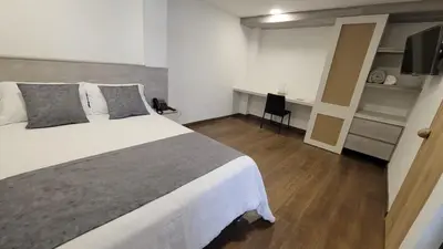 a bedroom with a large white bed and a desk at Hotel Piedras De Maní in Manizales