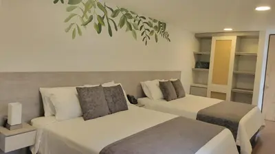 a bedroom with two beds and a plant at Hotel Piedras De Maní in Manizales