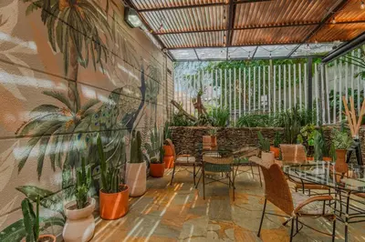 a patio with tables and chairs and plants on a wall at Hotel Poblado Alejandria in Medellín