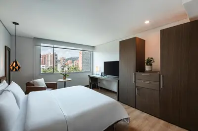 a hotel room with a bed and a desk and a window at Hotel Poblado Alejandria in Medellín