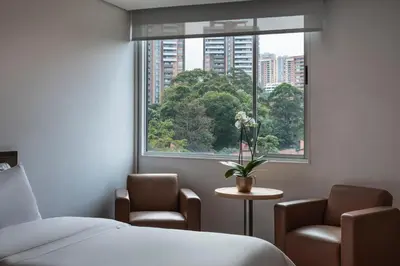 a room with a bed and two chairs and a window at Hotel Poblado Alejandria in Medellín