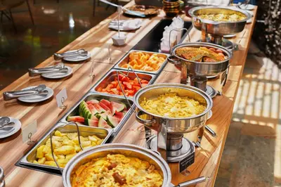 a table with many different types of food in trays at Hotel Poblado Alejandria in Medellín