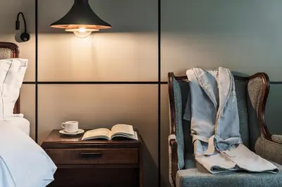 a bedroom with a bed and a table with a book and a coffee cup at Hotel Poblado Plaza in Medellín