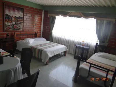 a small bedroom with two beds and a window at Palestina Ecohotel in Chinchiná