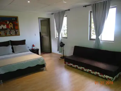 a bedroom with a bed and a couch and windows at Palestina Ecohotel in Chinchiná