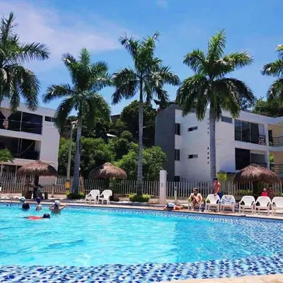 a swimming pool with palm trees and people in it at Apartasol in Santa Fe de Antioquia