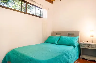 a bedroom with a bed with blue sheets and a window at La Casa de Piedra in Guatapé