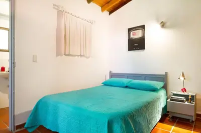 a bedroom with a blue bed and a window at La Casa de Piedra in Guatapé