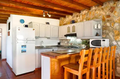 a kitchen with a white refrigerator and a table and chairs at La Casa de Piedra in Guatapé