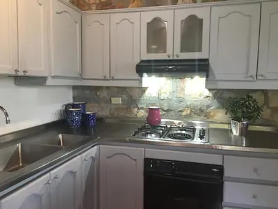 a kitchen with white cabinets and a stove top oven at La Casa de Piedra in Guatapé