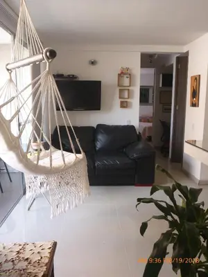 a living room with a black couch and a hanging hammock at Cerca al estadio familiar parqueadero piscina in Medellín