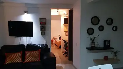 a living room with a couch and a flat screen tv at Cerca al estadio familiar parqueadero piscina in Medellín