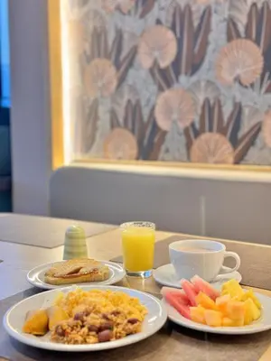 a table with two plates of food and a cup of orange juice at Tequendama Hotel Medellín - Estadio in Medellín