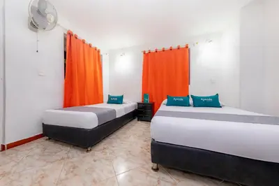 two beds in a room with orange curtains at Ayenda Florida Nueva in Medellín