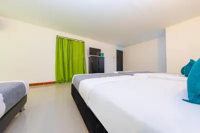 two beds in a room with a green curtain at Ayenda Florida Nueva in Medellín