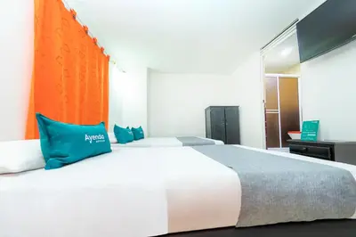 a bedroom with a large white bed with blue pillows at Ayenda Florida Nueva in Medellín