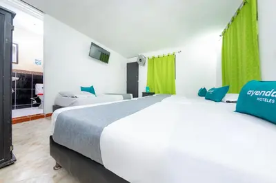 a bedroom with a large white bed and green curtains at Ayenda Florida Nueva in Medellín