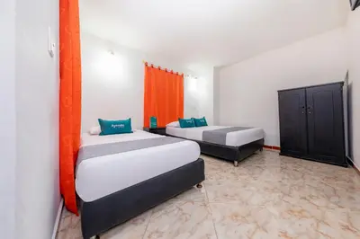 two beds in a room with orange curtains at Ayenda Florida Nueva in Medellín