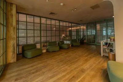 a waiting room with green chairs and windows at The Charlee Hotel in Medellín