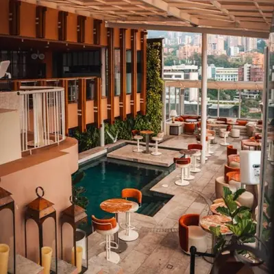 a hotel lobby with a pool and tables and chairs at The Charlee Hotel in Medellín