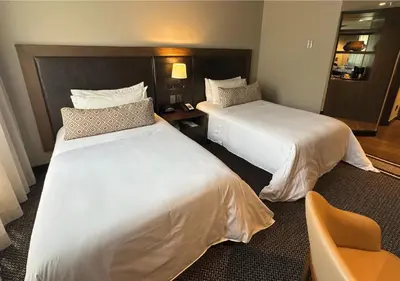 a hotel room with two beds and a chair at Movich Hotel Las Lomas in Rionegro