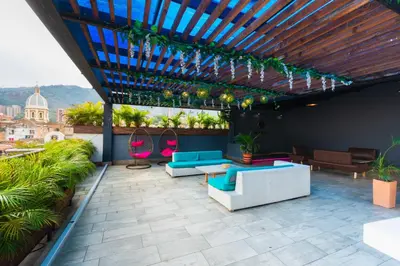 a patio with blue and pink furniture on a roof at Hotel Perlatto in Bello