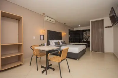 a bedroom with a bed and a table and chairs at Hotel Perlatto in Bello