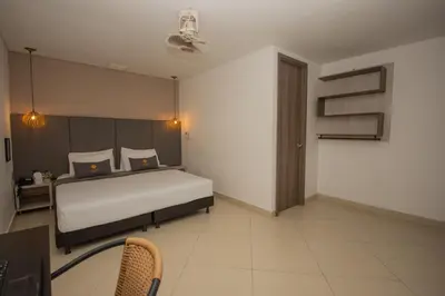 a bedroom with a bed and a desk with a chair at Hotel Perlatto in Bello