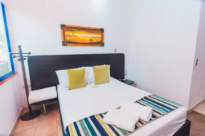a bedroom with a white bed and a chair at Hotel Guatatur in Guatapé