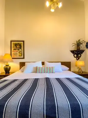 a large bed with a blue and white striped blanket at Hotel Mariscal Robledo in Santa Fe de Antioquia