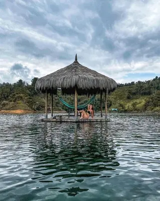 a woman laying in a hammock on a hut in the water at Levit Glamping - Hotel Guatapé Peñol in Guatapé