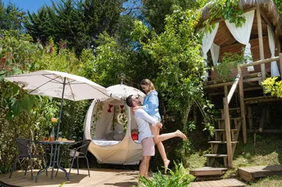 a man and a woman standing in front of a tent at Levit Glamping - Hotel Guatapé Peñol in Guatapé