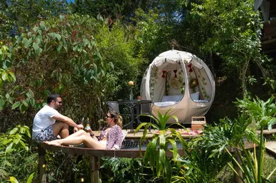 a man and woman sitting on a table in a garden at Levit Glamping - Hotel Guatapé Peñol in Guatapé