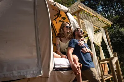 a man and a woman sitting on a bed in a tent at Levit Glamping - Hotel Guatapé Peñol in Guatapé