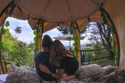 a couple sitting on a bed in a tent at Levit Glamping - Hotel Guatapé Peñol in Guatapé