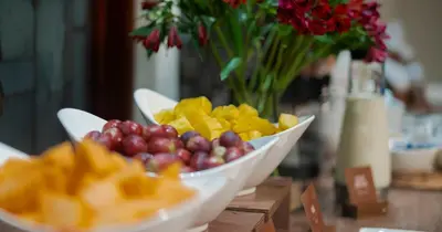 a bowl of fruit on a table with a vase of flowers at Hotel Casa Laureles in Medellín