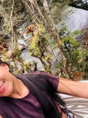 a young woman is smiling in front of a waterfall at Hostal Vista Hermosa in San Rafael