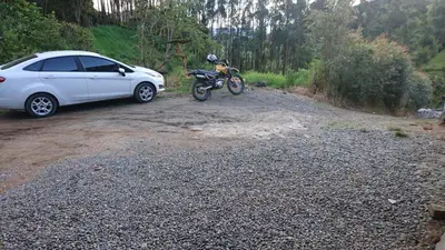 a motorcycle parked next to a white car on a dirt road at Hostal Encanto La Salada in Jardin