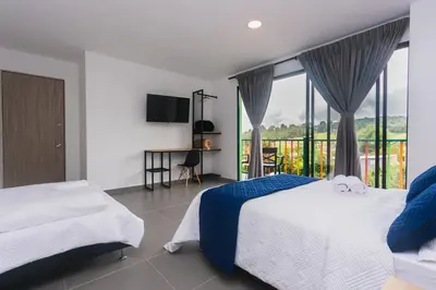 a bedroom with two beds and a balcony at Guatapé Country House Hotel in Guatapé