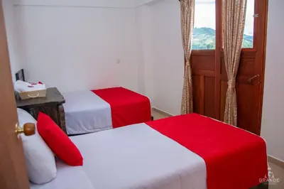 two beds in a hotel room with red and white sheets at Hotel Madre Laura Jericó in Jericó