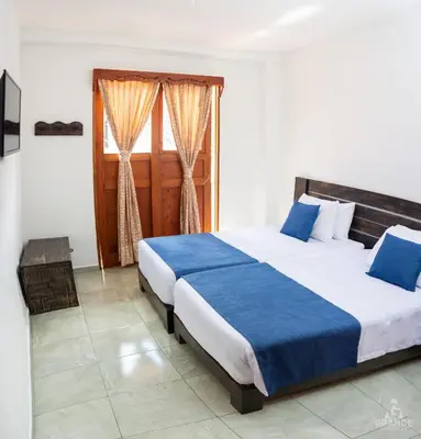 a bedroom with a large bed with blue sheets at Hotel Madre Laura Jericó in Jericó